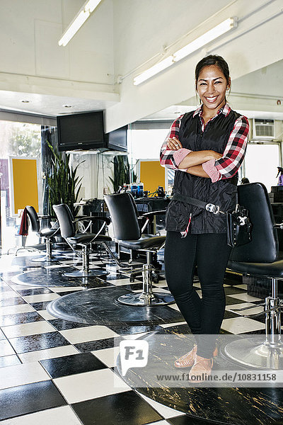 Hispanischer Friseur lächelnd im Salon