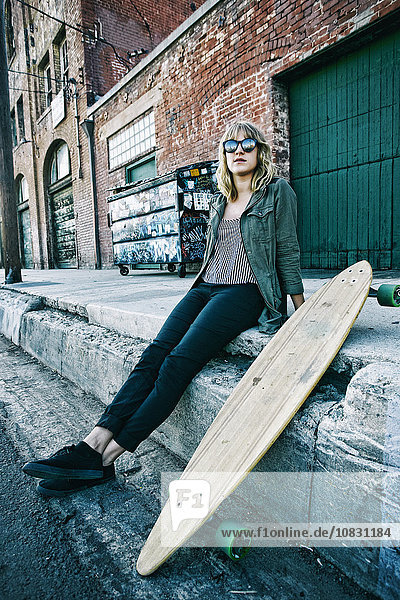 Caucasian woman sitting with skateboard