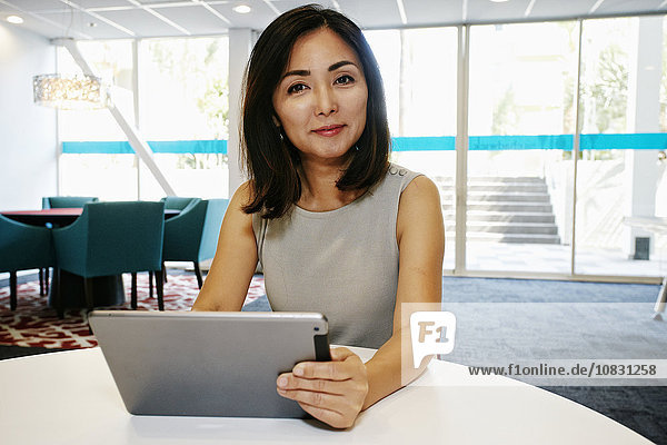 Japanische Geschäftsfrau benutzt digitales Tablet im Büro
