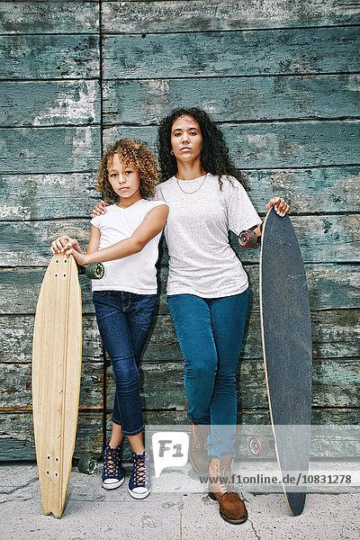 Gemischtrassige Mutter und Tochter halten Skateboards