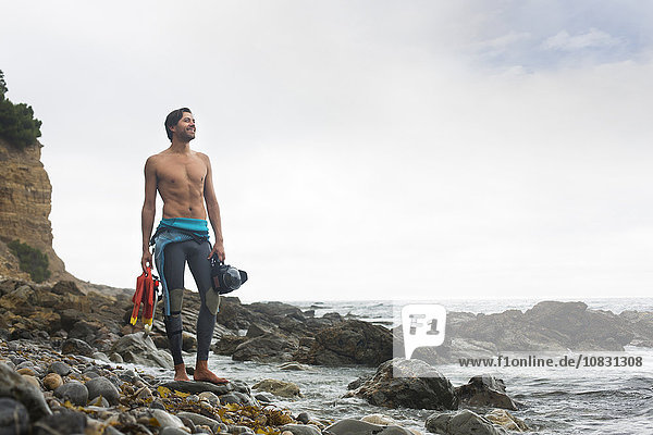 Hispanic diver wearing wetsuit on beach