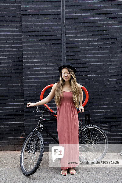 Asian woman standing with bicycle