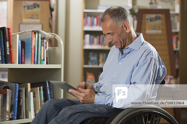 Kaukasischer Mann benutzt digitales Tablet in einer Bibliothek