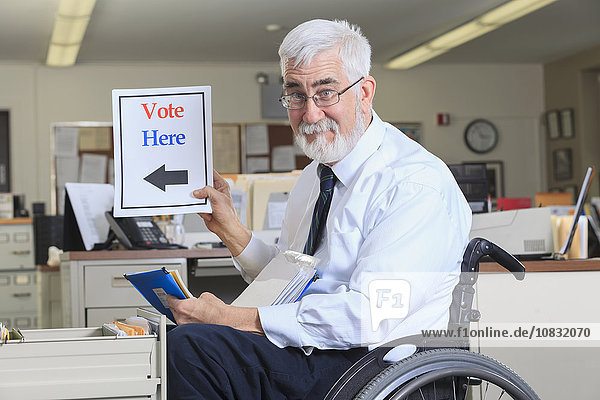 Caucasian businessman holding voting sign in office