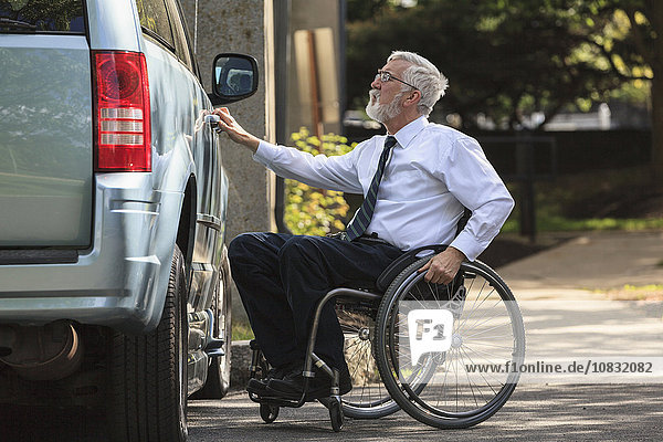 Kaukasischer Geschäftsmann im Rollstuhl öffnet die Tür eines Lieferwagens