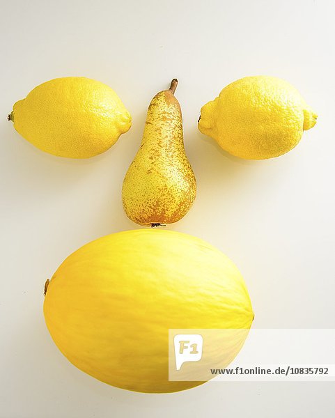 Gesicht aus gelben Früchten vor weissem Hintergrund