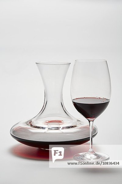 Glaskaraffe und ein Glas mit Rotwein auf weißem Hintergrund