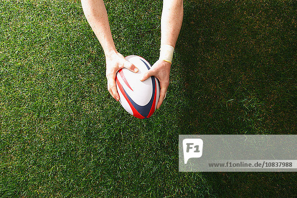 Mann hält Rugbyball auf Gras