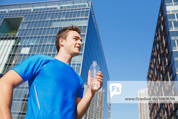 Young Caucasian man drinking water in metropolitan area