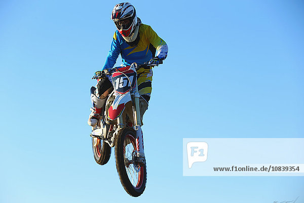 Motocross biker jumping over dirt track