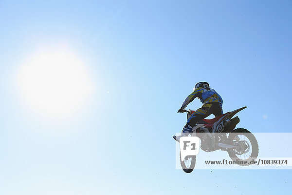 Motocross biker jumping over dirt track