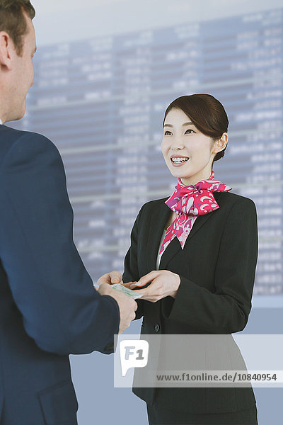Eine attraktive japanische Flugbegleiterin hilft einem Kunden am Flughafen