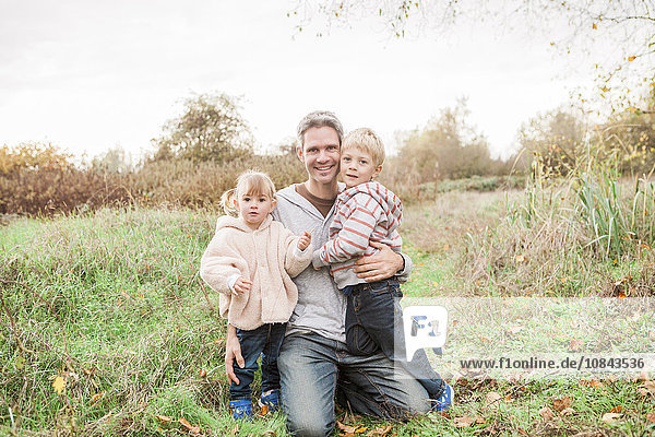 Portrait lächelnder Vater und Kleinkinder im Herbstpark