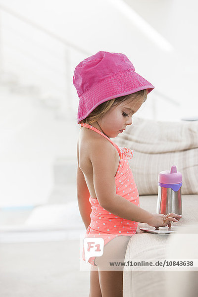 Kleinkind Mädchen im Badeanzug mit digitalem Tablett am Sofa
