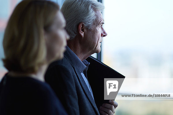 Pensive businessman and businesswoman looking through window