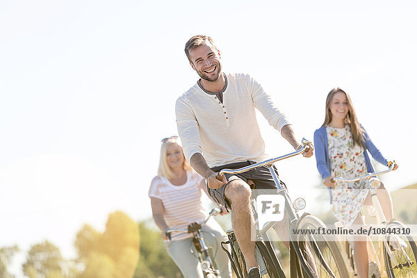 Lächelnder junger Mann beim Radfahren mit Frauen