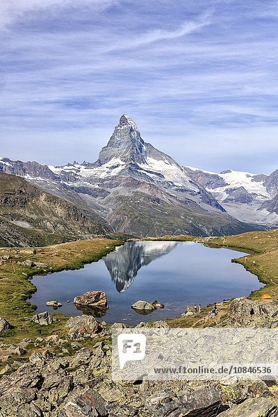Hikers admire the Matterhorn reflected in Lake Stellisee  Zermatt  Canton of Valais  Pennine Alps  Swiss Alps  Switzerland  Europe