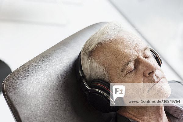 liegend liegen liegt liegendes liegender liegende daliegen Senior Senioren Mann zuhören Kopfhörer Musik Klassisches Konzert Klassik zurücklehnen