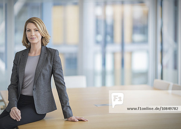 Portrait confident businesswoman leaning on conference table