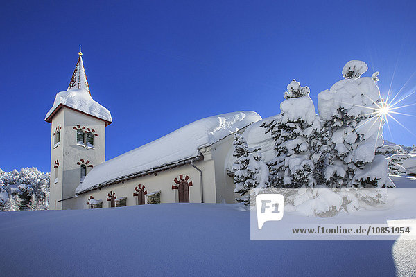 Strahlen der Wintersonne beleuchten die Schneelandschaft und die typische Kirche  Maloja  Engadin  Kanton Graubünden  Schweiz  Europa
