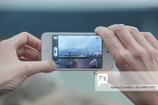 Hände fotografieren ein Cunard-Kreuzfahrtschiff mit einem iPhone  Vereinigtes Königreich  Europa