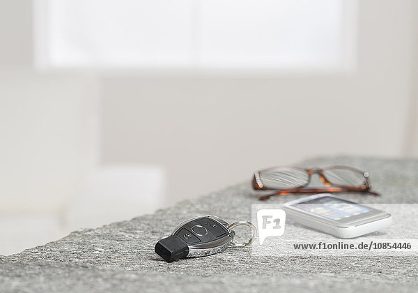 Autoschlüssel  Smartphone und Brille liegen auf einem Tisch
