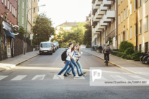 Side view of teenagers crossing road in city