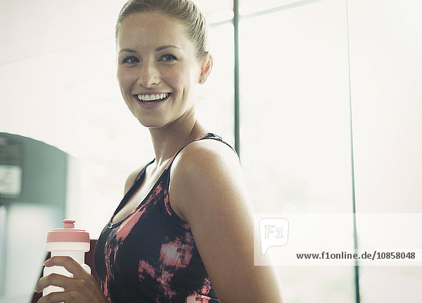 Portrait lächelnde Frau mit Wasserflasche im Fitnessstudio