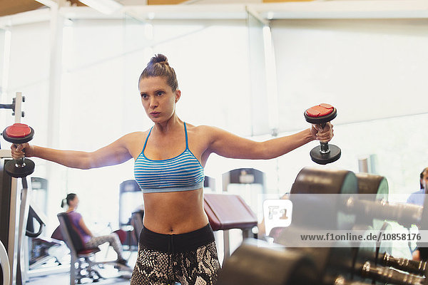 Fokussierte Frau beim Kurzhantel-Brustfliegen im Fitnessstudio