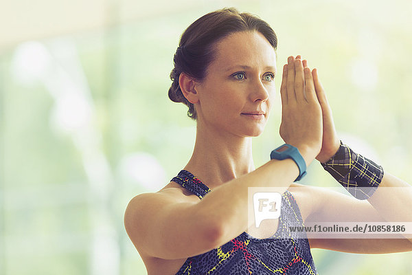 Calm woman with hands at prayer position in yoga class