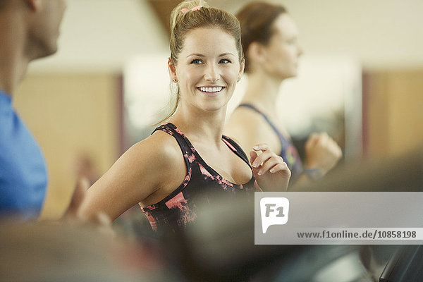 Lächelnde Frau beim Joggen auf dem Laufband im Fitnessstudio