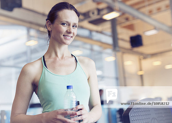 Portrait lächelnde Frau trinkt Wasser im Fitnessstudio