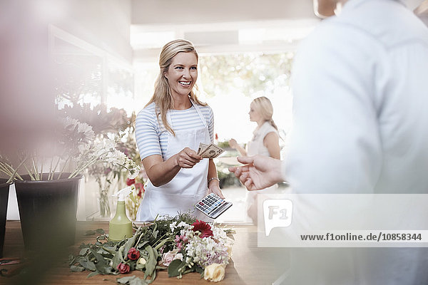 Lächelnder Florist mit Kundenwechsel im Blumenladen