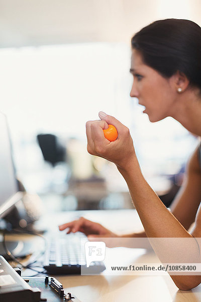 Geschäftsfrau quetscht Stressball am Computer im Büro