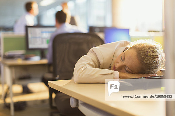 Geschäftsfrau schläft auf dem Schreibtisch im Büro