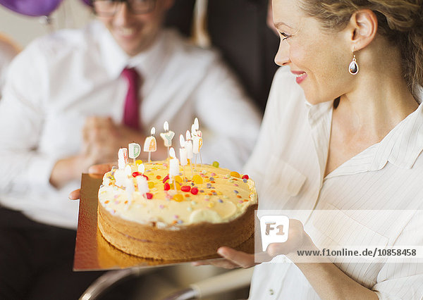 Lächelnde Geschäftsfrau mit Geburtstagskuchen und Kerzen