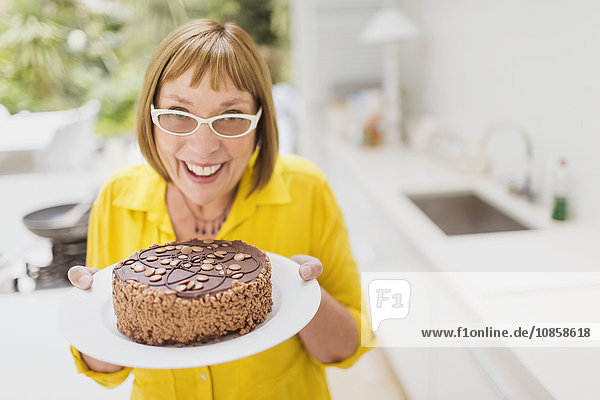 Portrait smiling mature woman holding chocolate cake