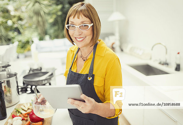 Portrait smiling mature woman with digital tablet cooking in kitchen