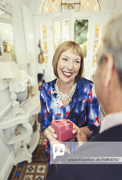 Smiling mature woman receiving gift from husband