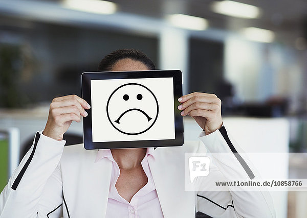 Portrait of businesswoman covering face with digital tablet in office