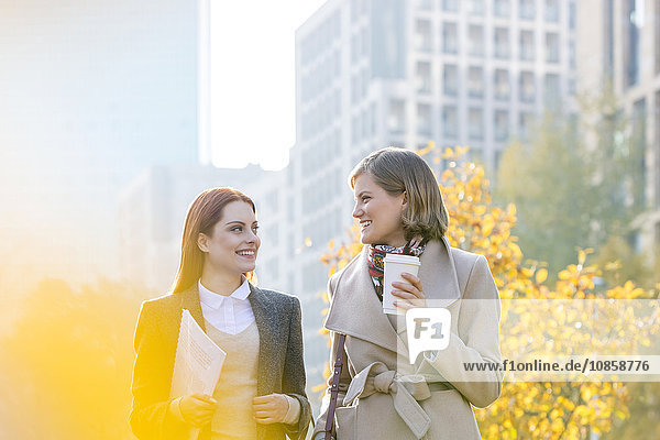 Businesswomen walking with coffee in city