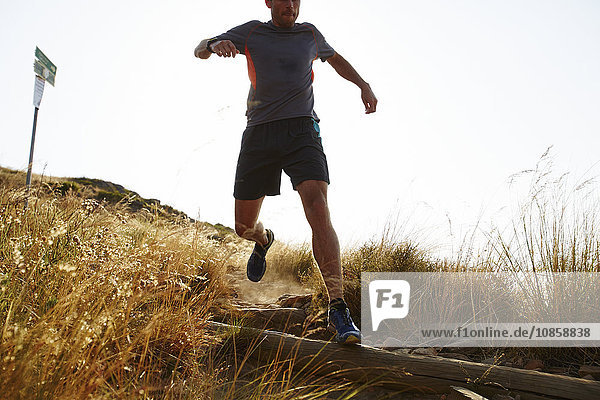 Male runner descending trail hillside