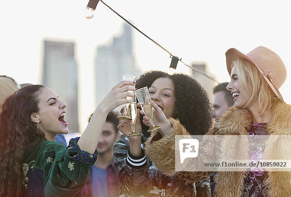 Begeisterte junge Frauen trinken Champagnergläser auf der Dachparty