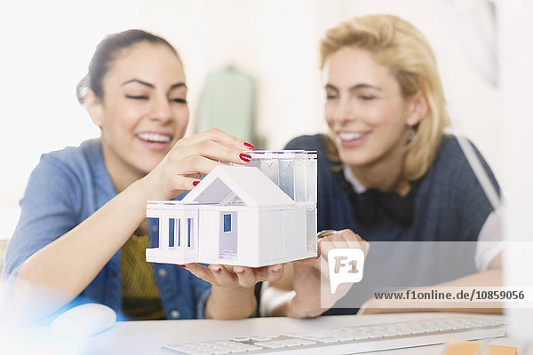 Young female architects assembling house model