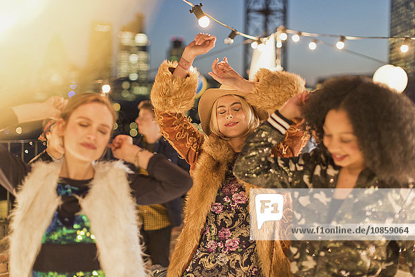 Young adult women dancing at nighttime rooftop party