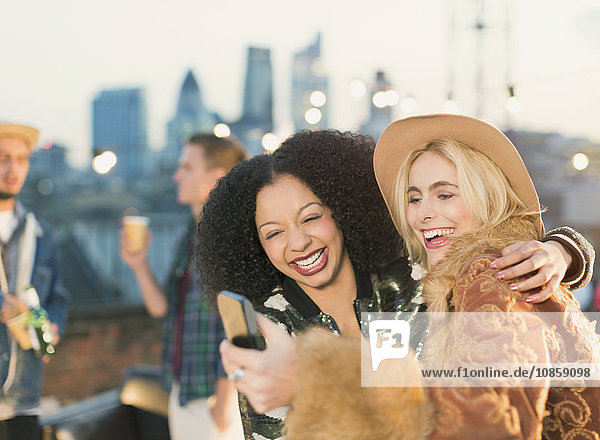 Lachende junge Frauen nehmen Selfie auf Dachparty