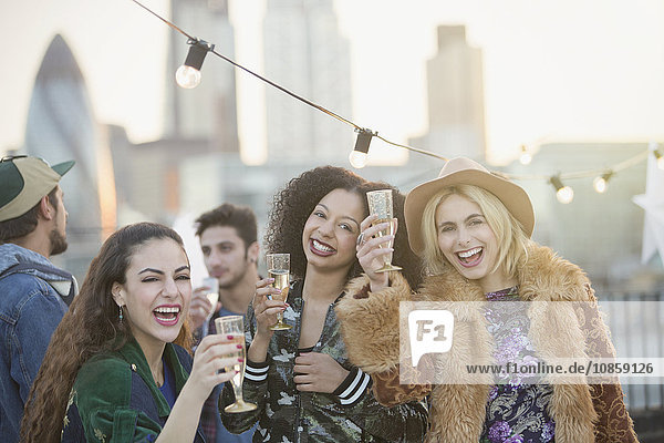 Portrait begeisterte junge Frauen beim Champagnertrinken auf der Dachparty