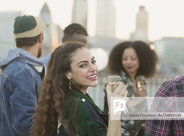 Portrait lächelnde junge Frau trinkt Champagner auf der Dachparty