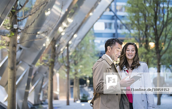Businessman and businesswoman using digital tablet in courtyard