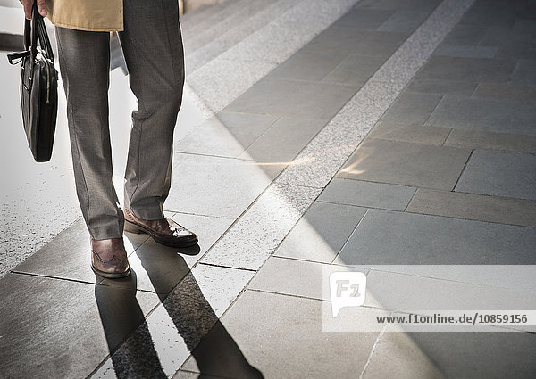 Corporate businessman standing on sunny pavement